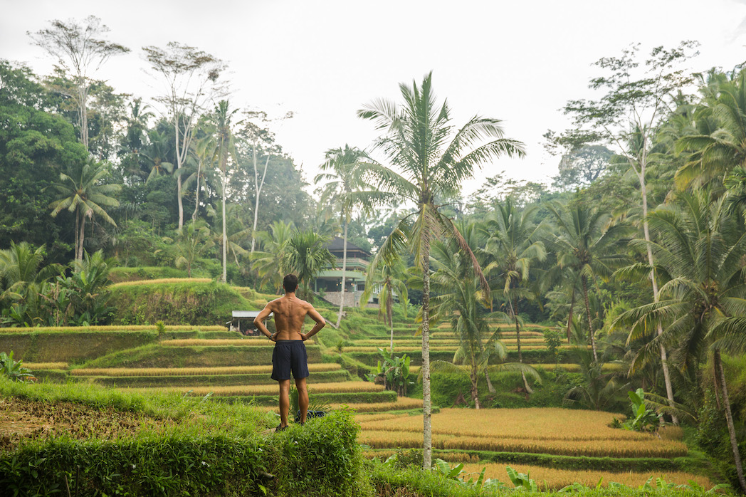 Traveler standing above rice terraces in Bali, embracing solitude during an Unsettled experience